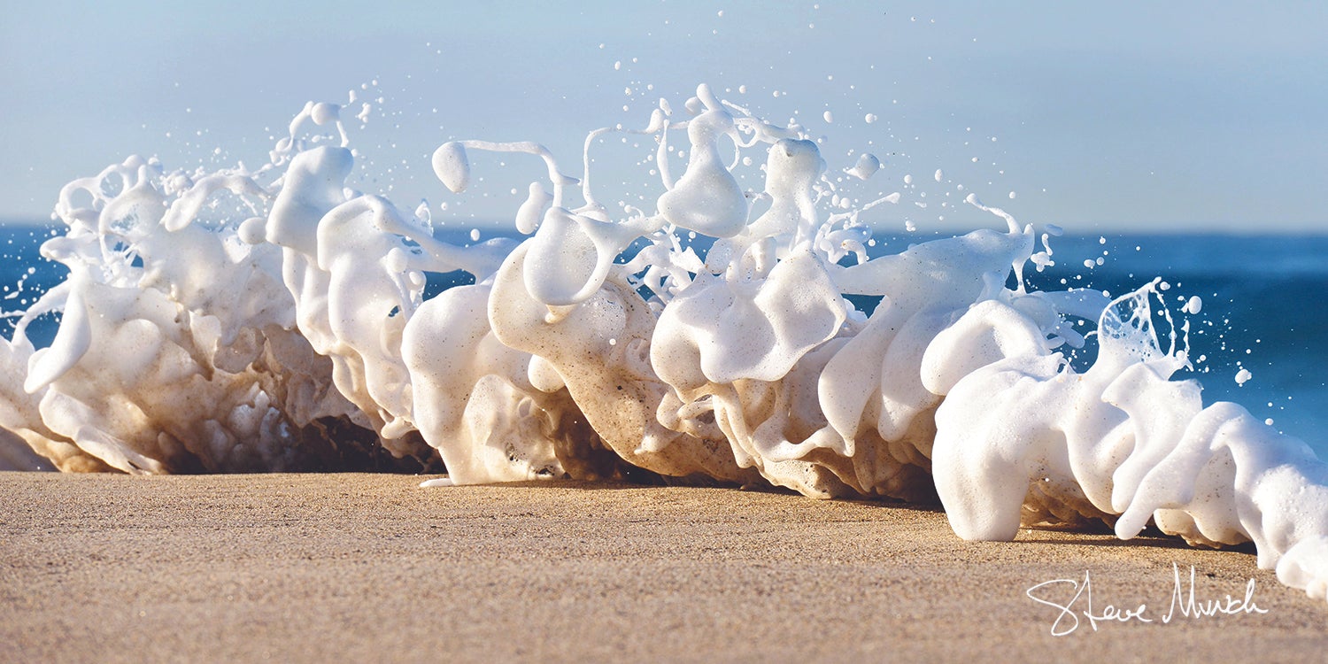 Nature photography wall art of fresh foam capturing grains of sand and carrying it away as the tide bounces in an effervescent show.